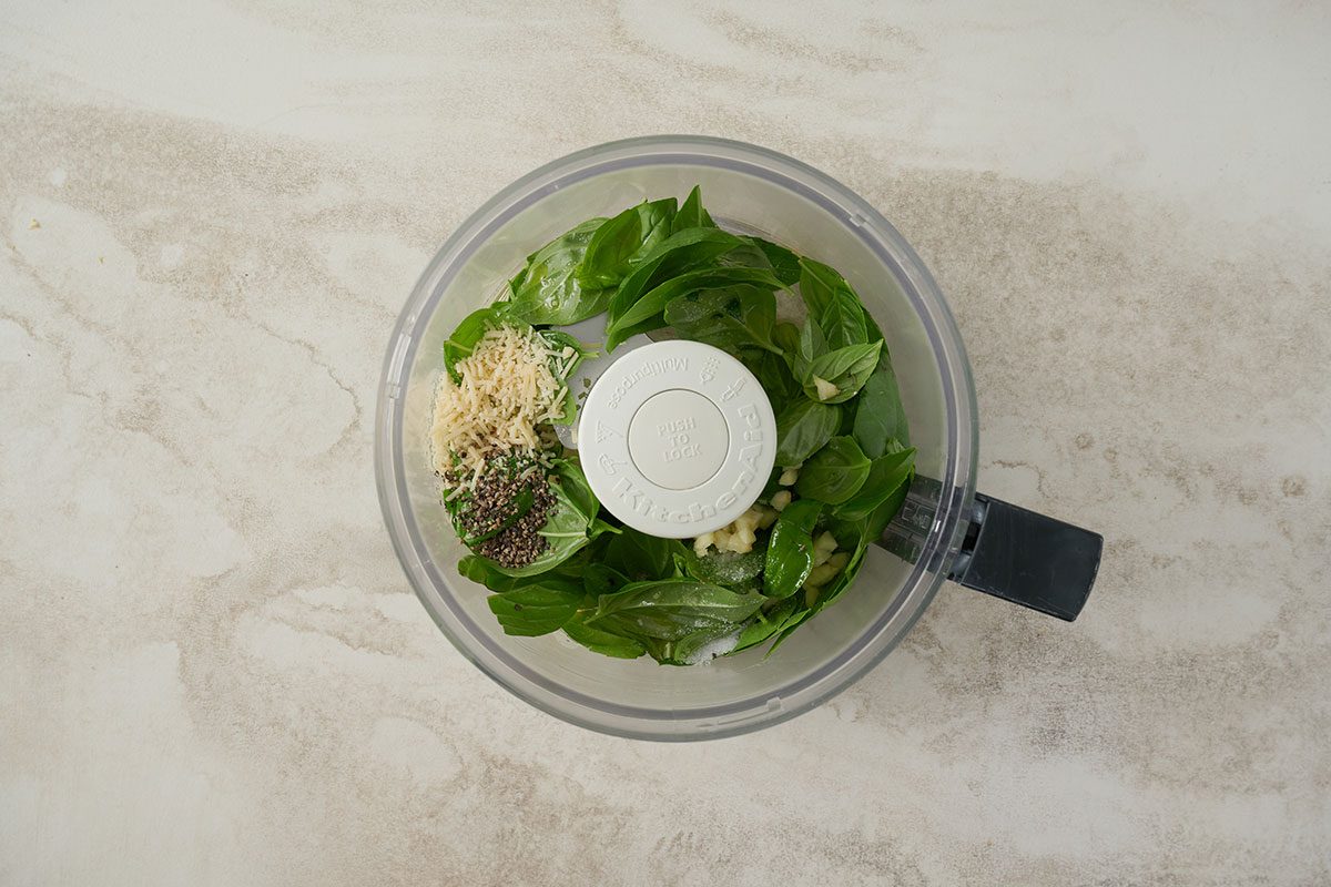 Overhead view of fresh basil, oil, garlic, and Parmesan cheese in a food processor for the Taste of Home Basil Salmon recipe.