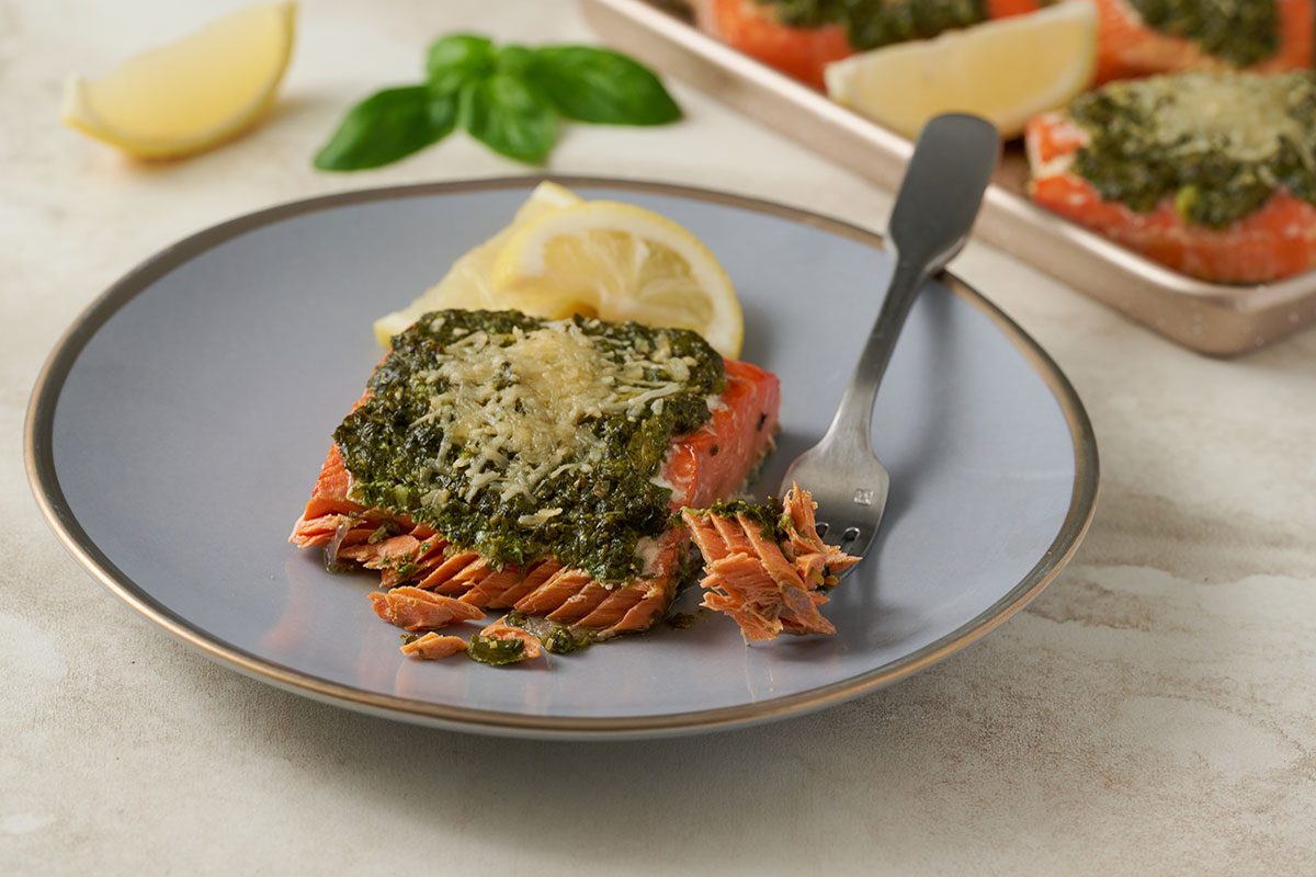 Close-up horizontal shot of the Taste of Home Basil Salmon, highlighting the creamy pesto and melted cheese on the flaky salmon fillets.