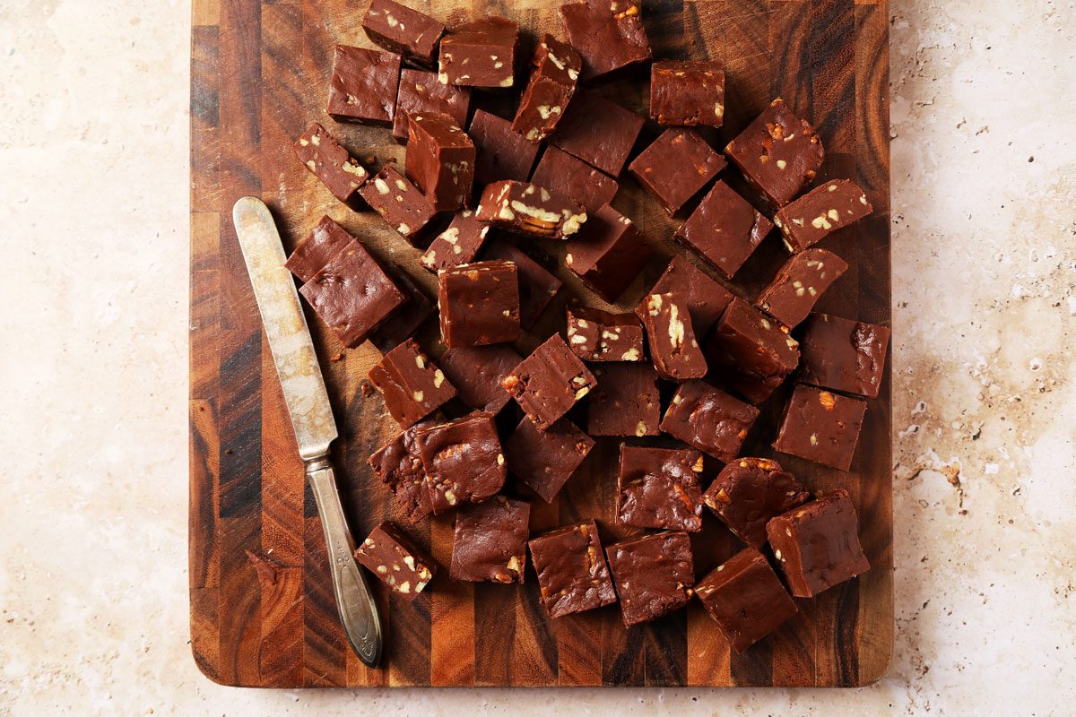 Process of making Taste of Home's Velveeta Fudge sliced on a cutting board on a brown marble surface.
