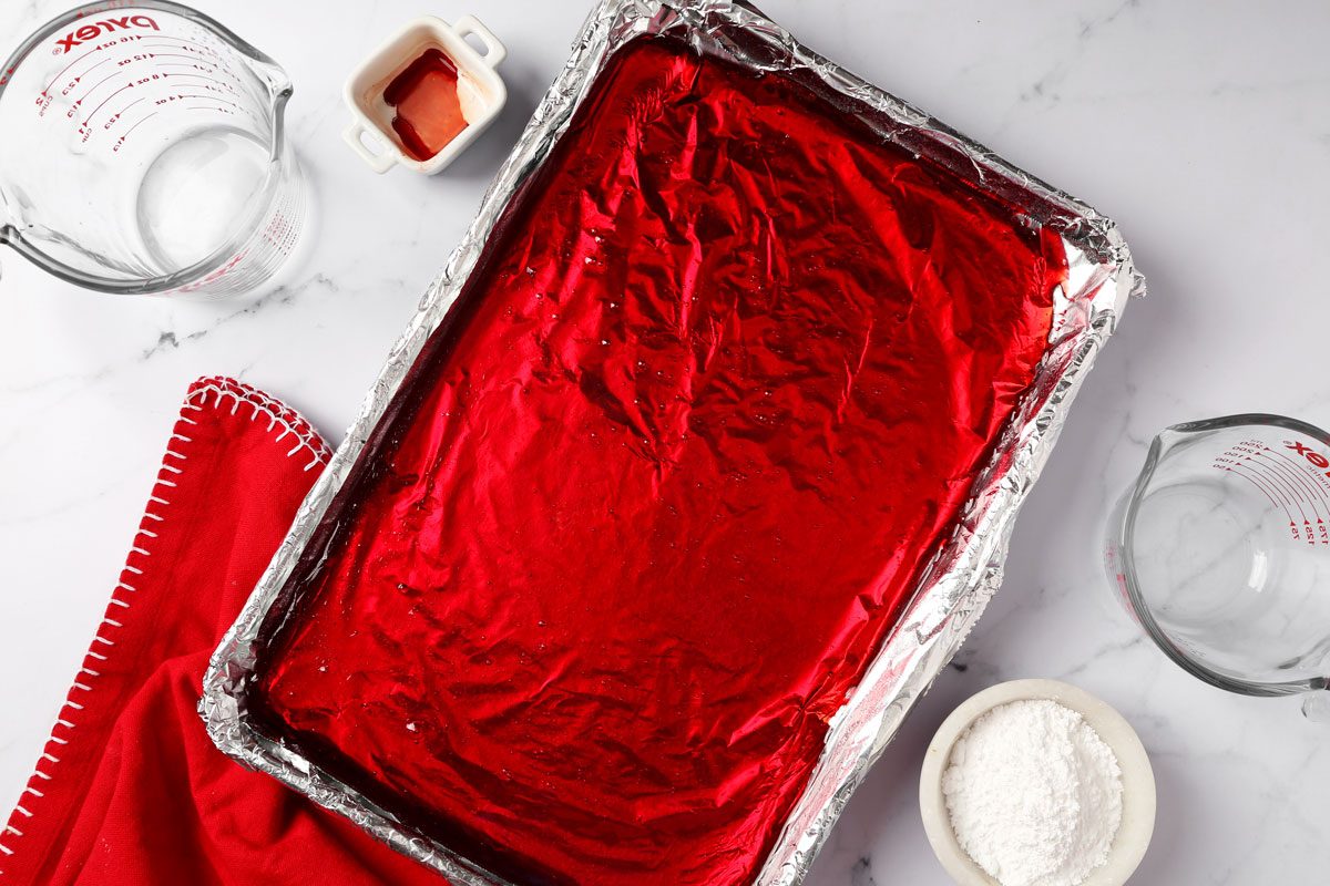 Process of making Taste of Home's cinnamon hard candy in a baking sheet on a grey marble surface.