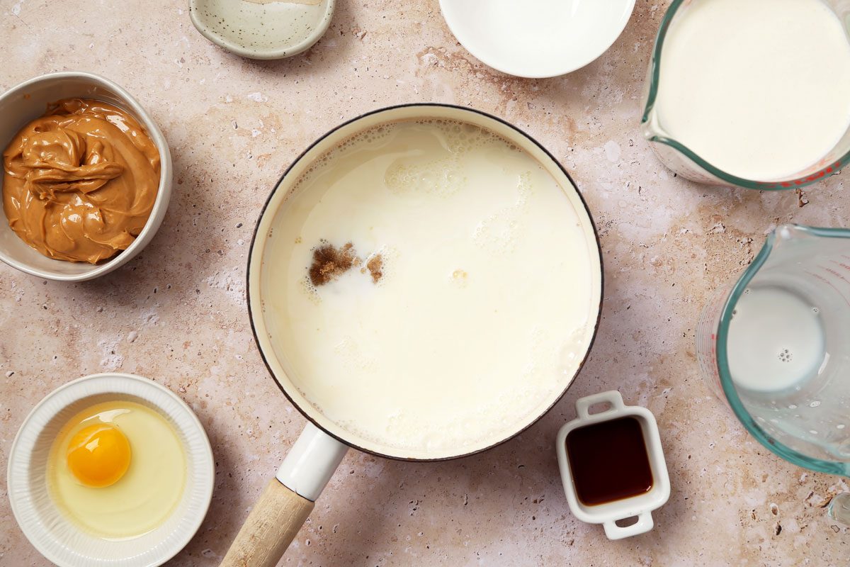 Process of making Taste of Home's Peanut Butter Ice Cream in an ice cream maker on a brown marble surface.