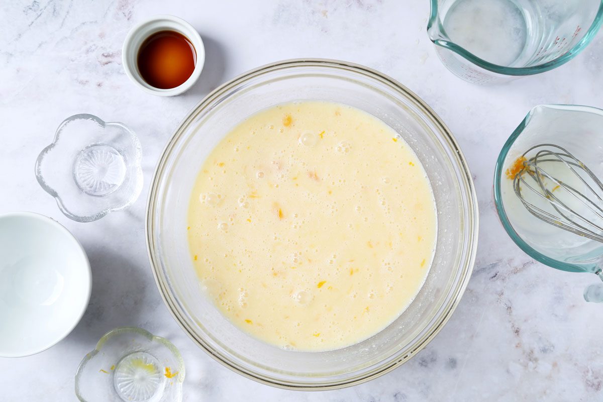 Process of making Taste of Home's Orange Sherbet in a large mixing bowl on a white marble surface with an orange towel.