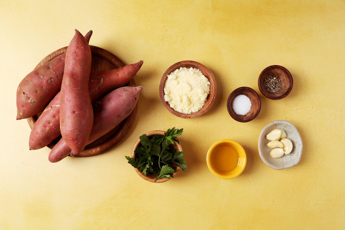 Ingredients for Taste of Home's Smashed Sweet Potatoes laid out in small bowls on a yellow surface.