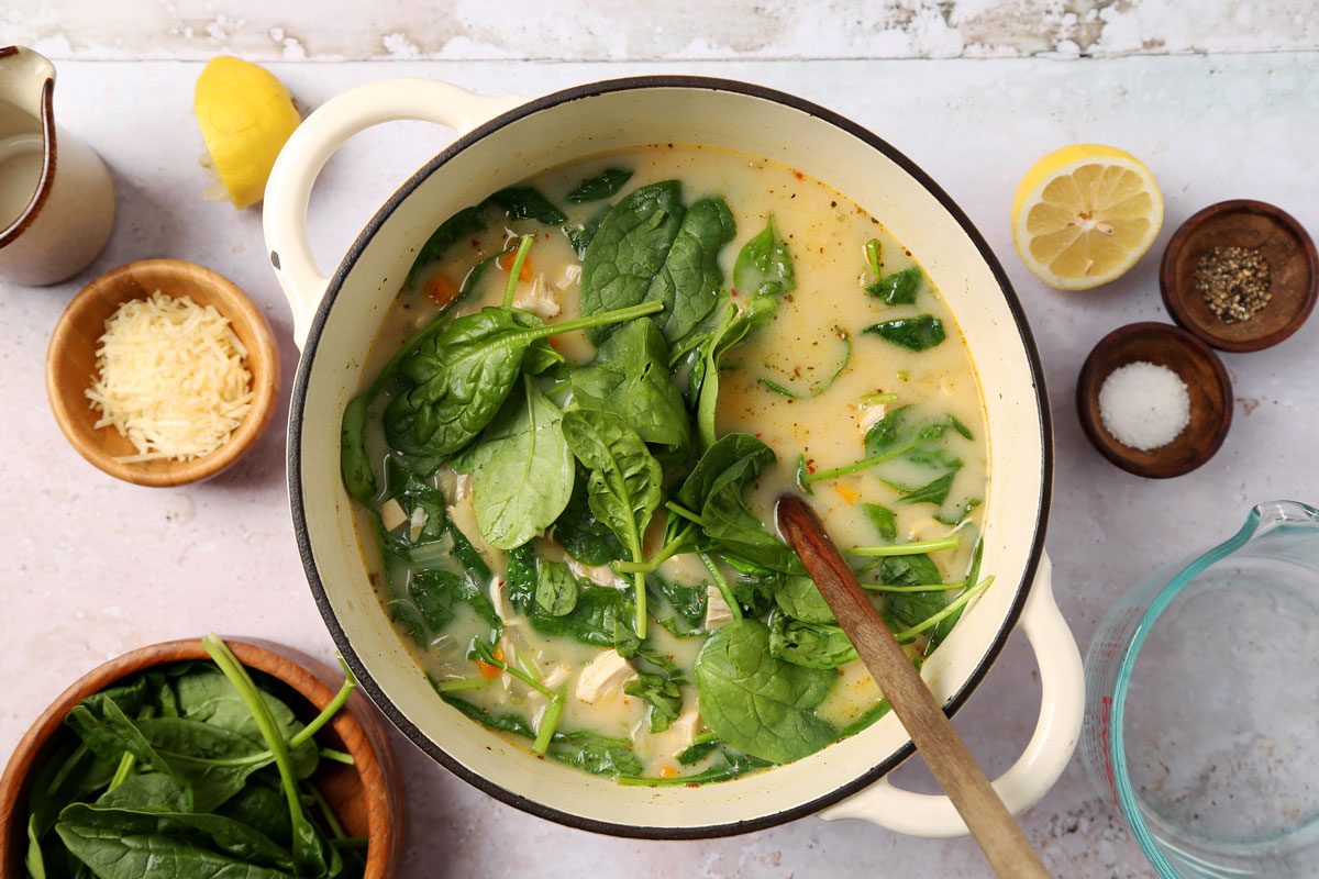 process of making Taste of Home's Chicken Florentine Soup in a dutch oven on a grey surface.