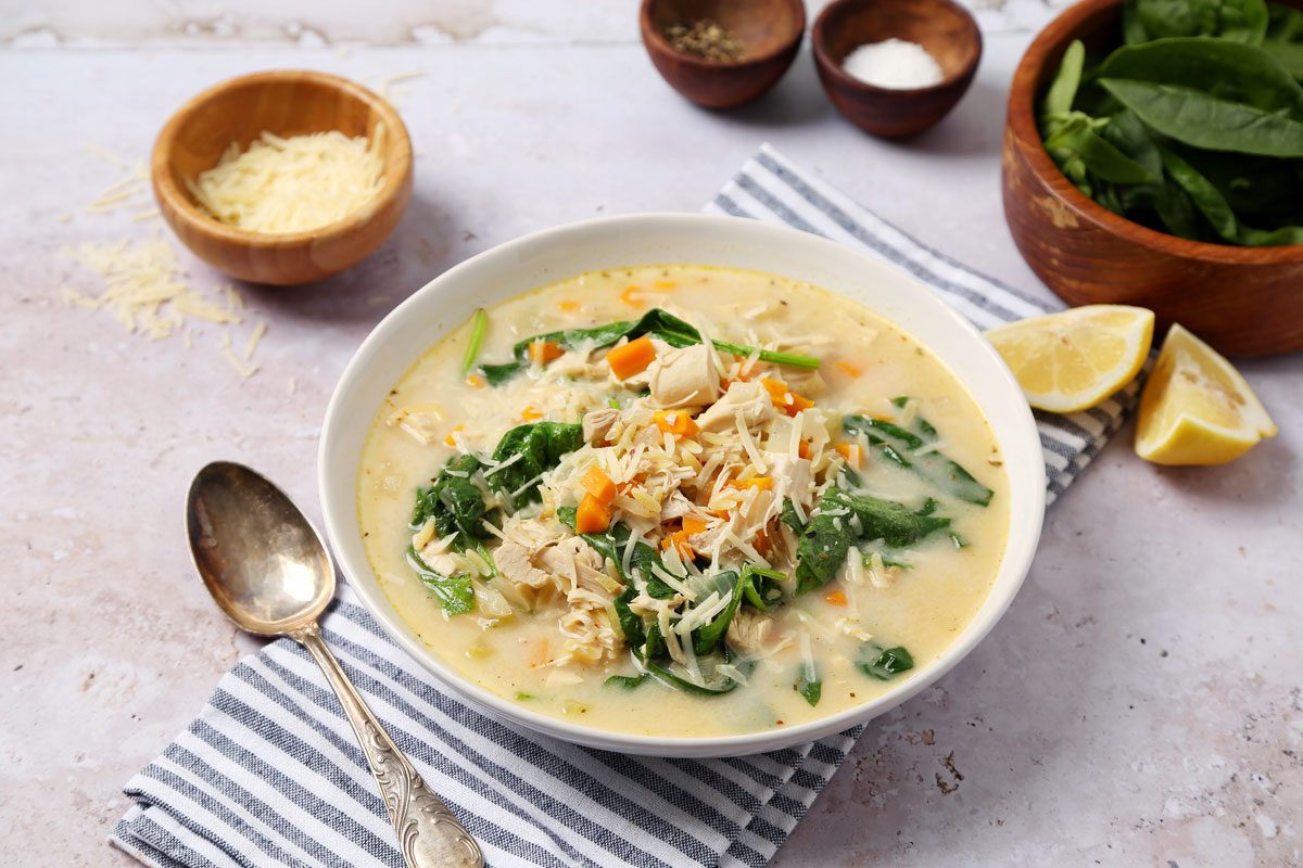 Close up of Taste of Home's Chicken Florentine Soup served in a white bowl on a grey surface.