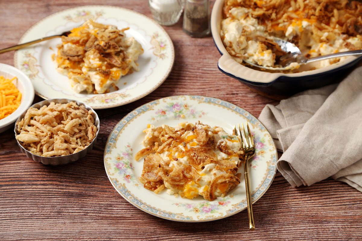Close up of Taste of Home's French Onion Chicken Casserole served on a plates on a brown wooden surface.