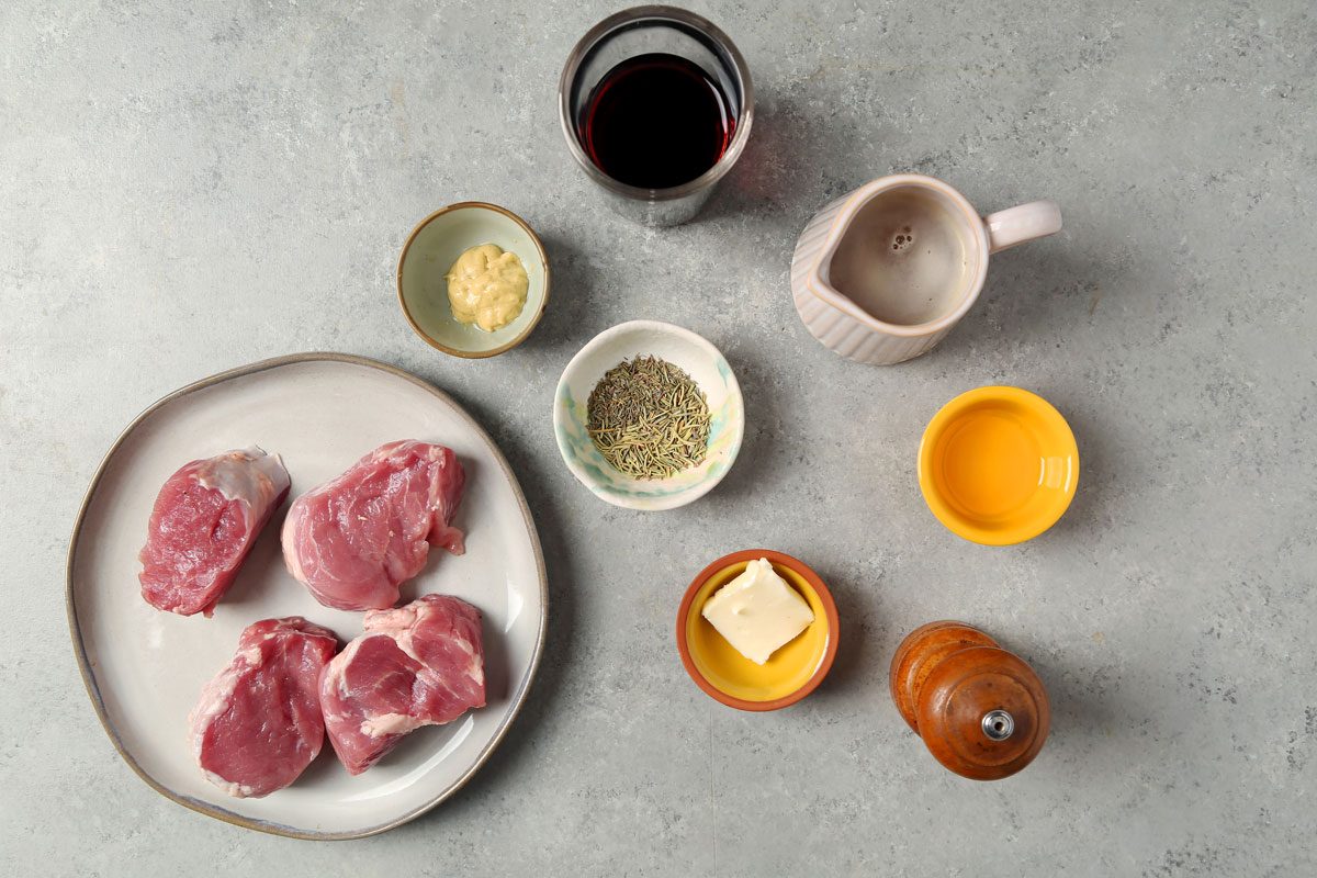 Close up of Taste of Home's Pork and Red Wine Sauce served on a large grey plate on a grey marble surface.