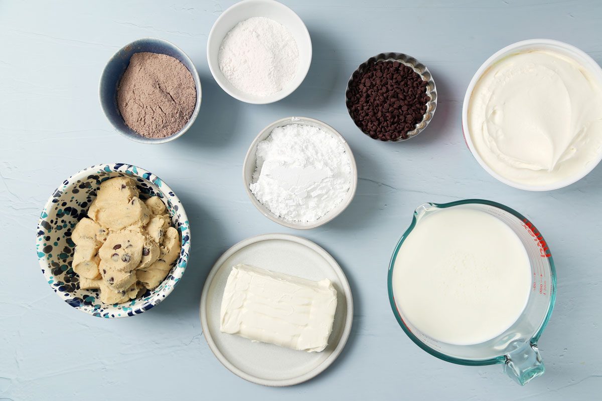 Ingredients laid out in small bowls for Taste of Home's Chocolate Chip Cookie Delight on a light blue surface.