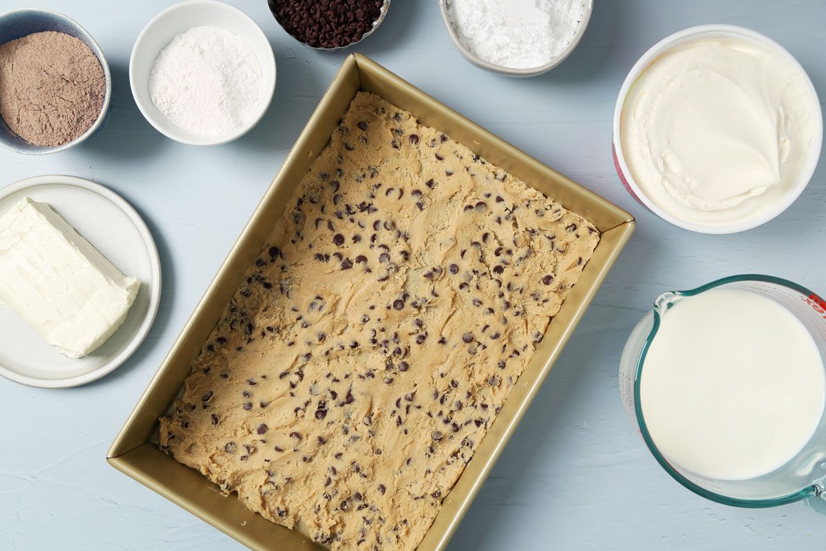 Process of making Taste of Home's Chocolate Chip Cookie Delight in a baking pan on a light blue surface.