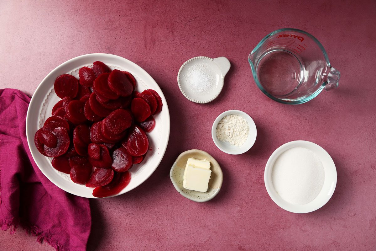 Close up of Taste of Home's Harvard Beets served on white plates on a magenta surface.