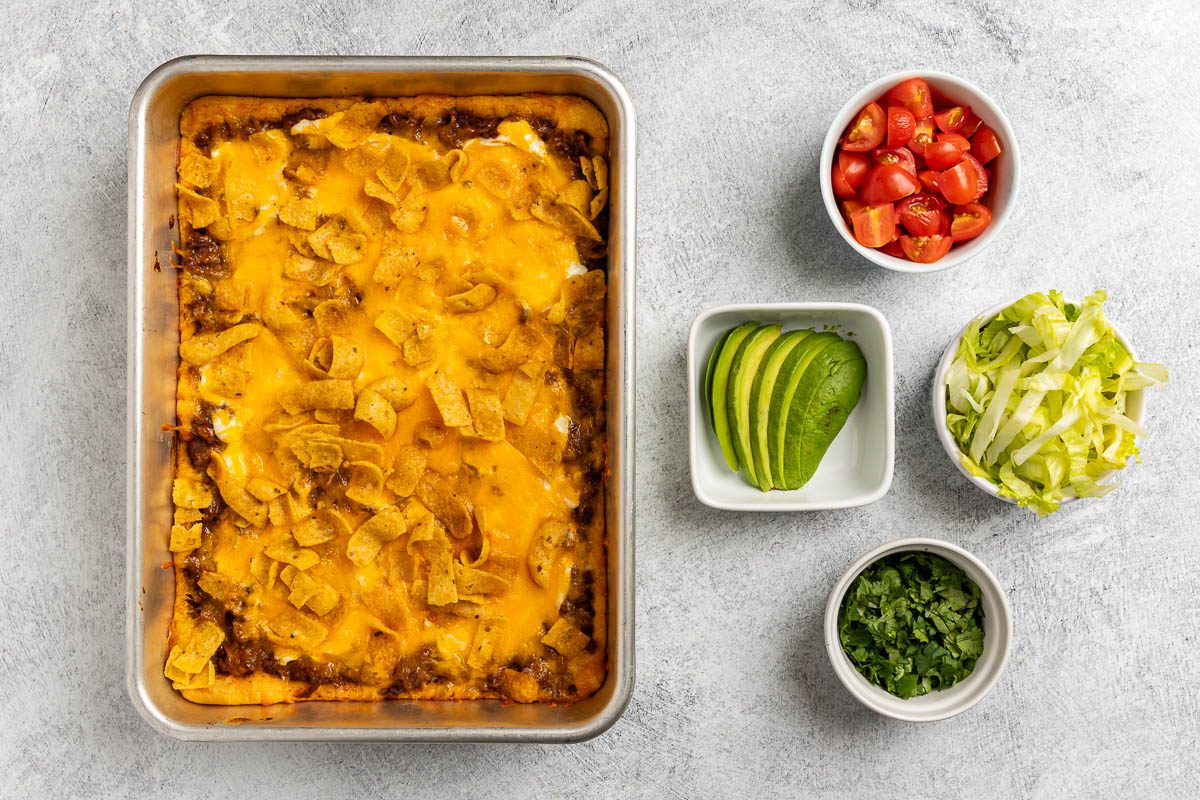 Crescent Roll Taco Bake in a pan with toppings to the side
