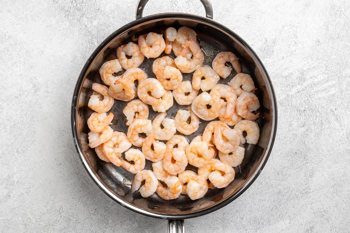 cooking the shrimp in a skillet.