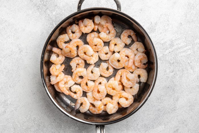 cooking the shrimp in a skillet.