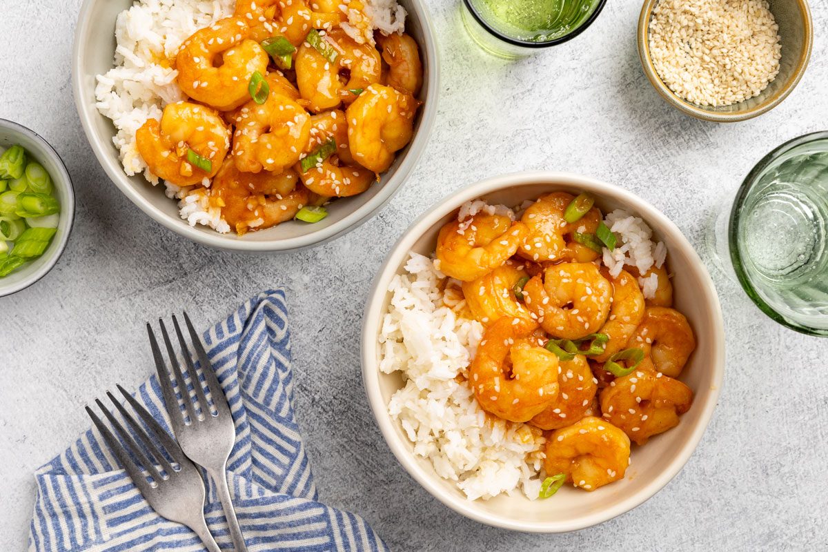 Teriyaki Shrimp portioned into bowls with rice, green onions and sesame seeds as garnish.