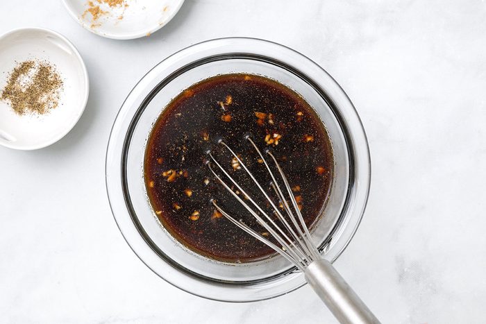 Sugar, soy sauce, vinegar, garlic, ginger and pepper mixed together in a bowl for step one of Teriyaki Chicken Thighs recipe for Taste of Home