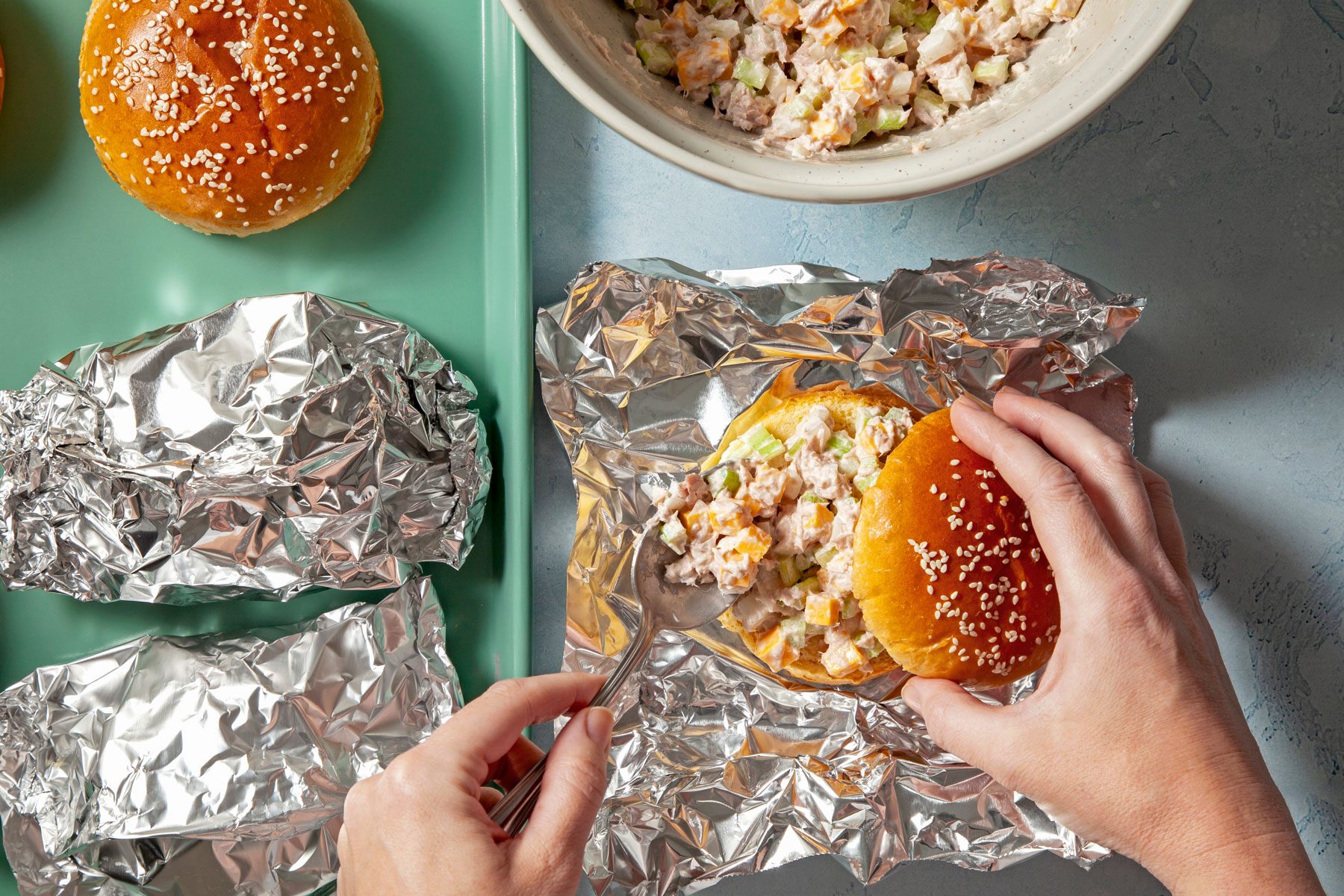 Bun top being placed on tuna salad spread over bun bottom.
