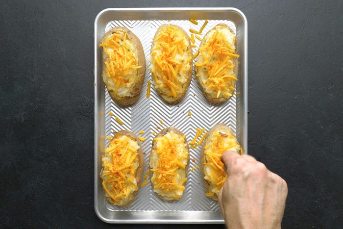 Sprinkling cheese on stuffed potatoes