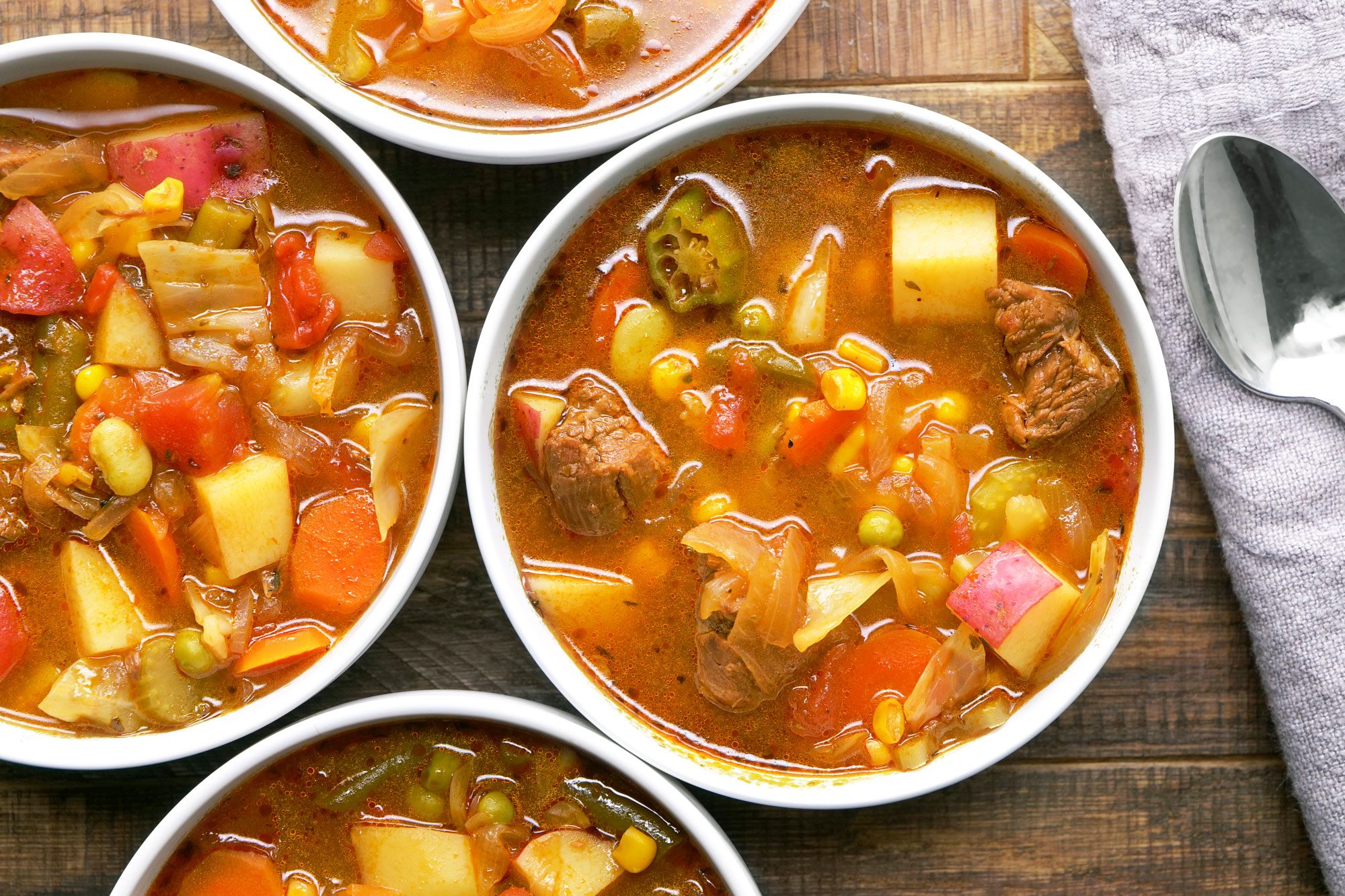 A hearty vegetable beef soup are arranged on a wooden table