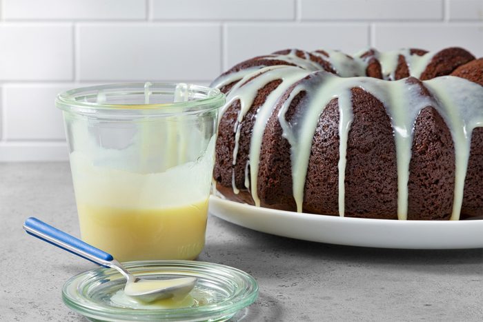 Table view shot of White Chocolate Sauce; transfer into jar with lid; spoon over cake; grey surface;