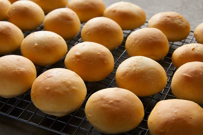 Rows of freshly baked golden brown rolls cooling on a wire rack.