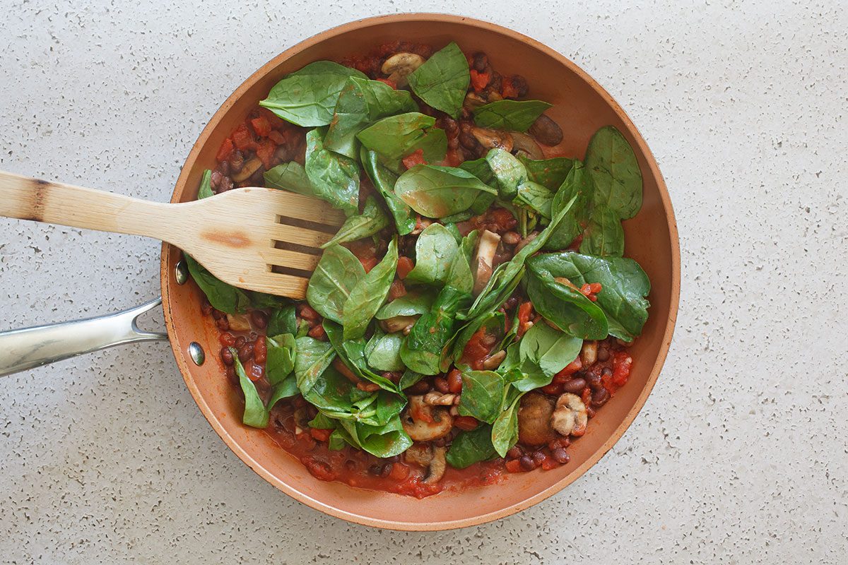 Vegetables cooking in skillet, spinach, mushrooms, tomatoes