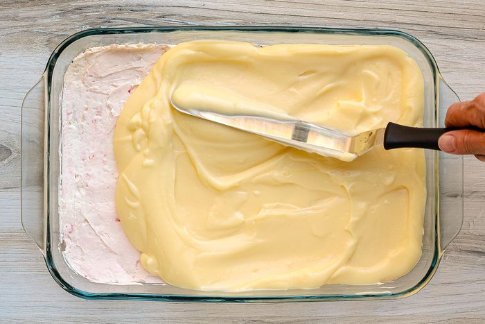 The pudding is spread over the cream cheese and candy cane layer.