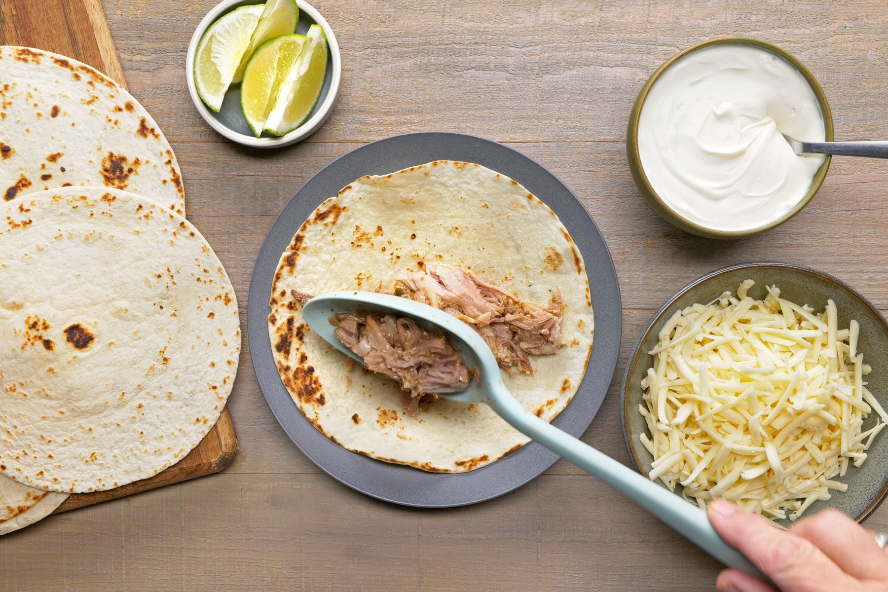 shredded pork being added to tortillas