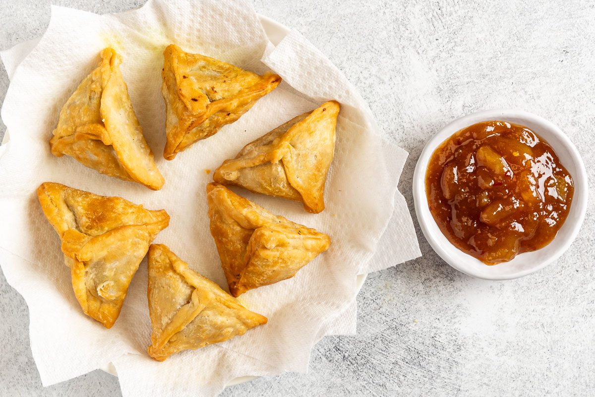 Taste of Home Chicken Samosa photo of the fried samosas with a side of chutney.
