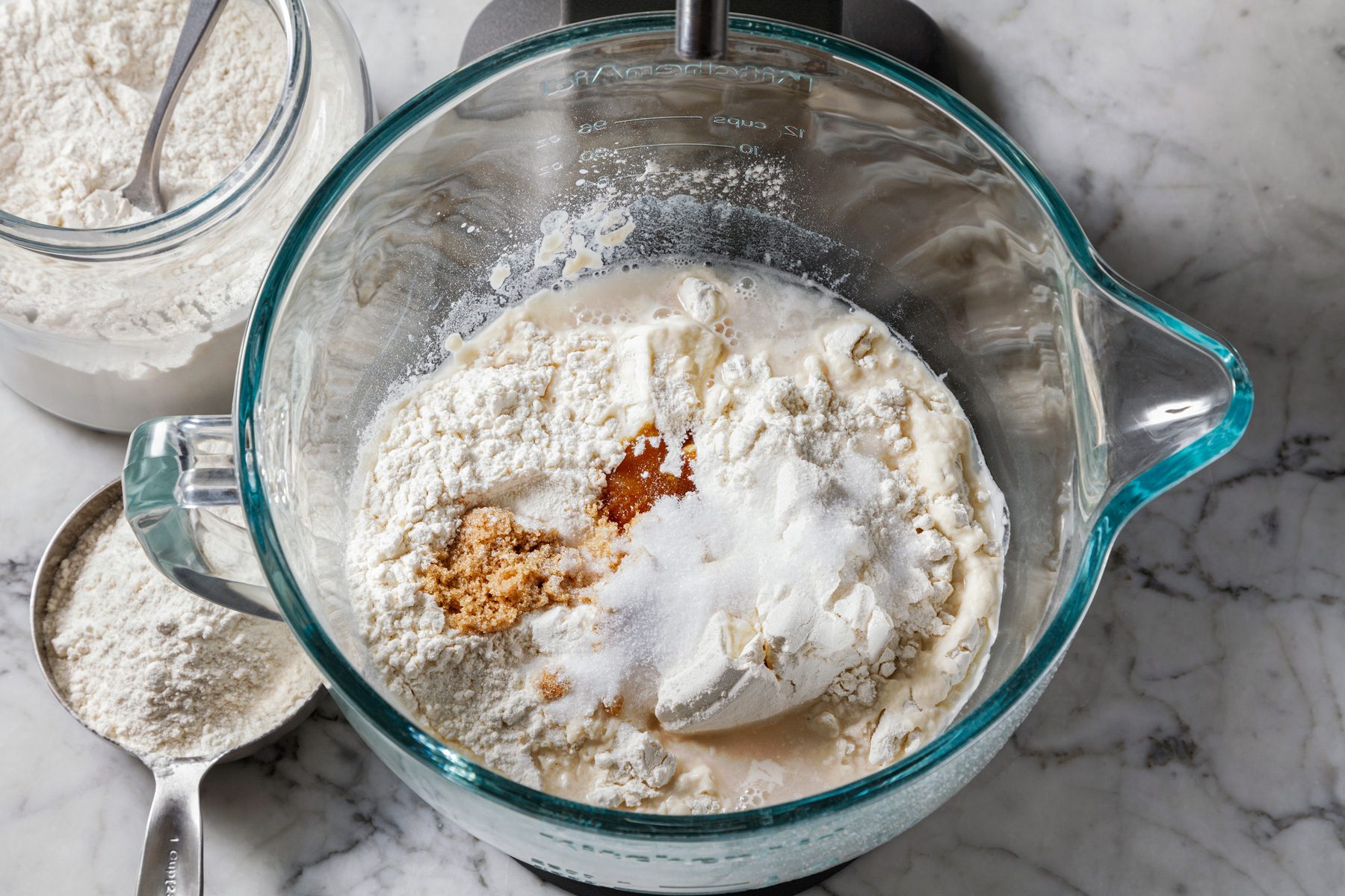 Overhead shot of adding flour, brown sugar, and salt to the stand mixer; mixing on low for 2-3 minutes on a marble surface.
