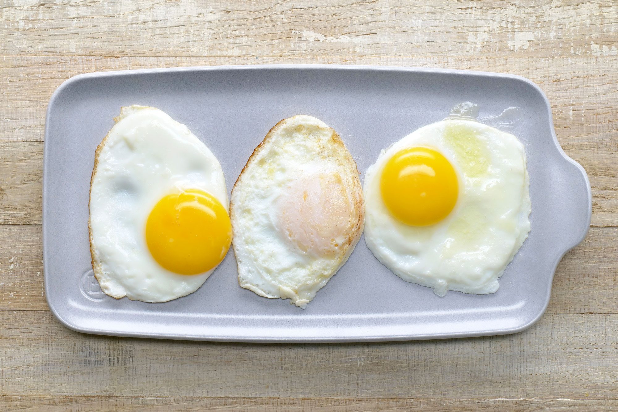 Overhead shot of Fried Eggs; serve on large plate; wooden surface;