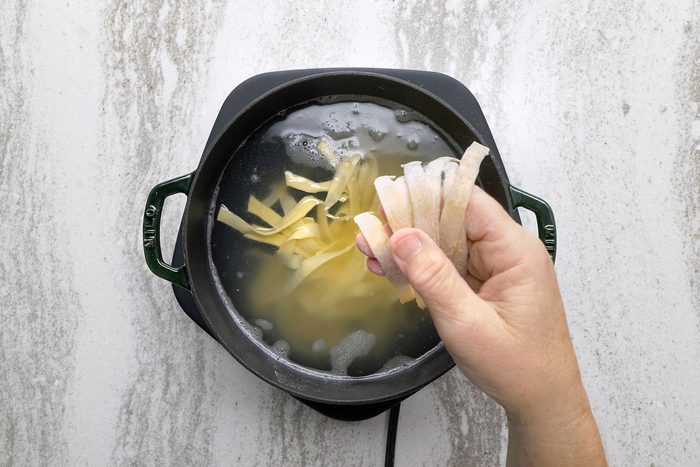 Putting handmade noodles in boiling water in a large pot