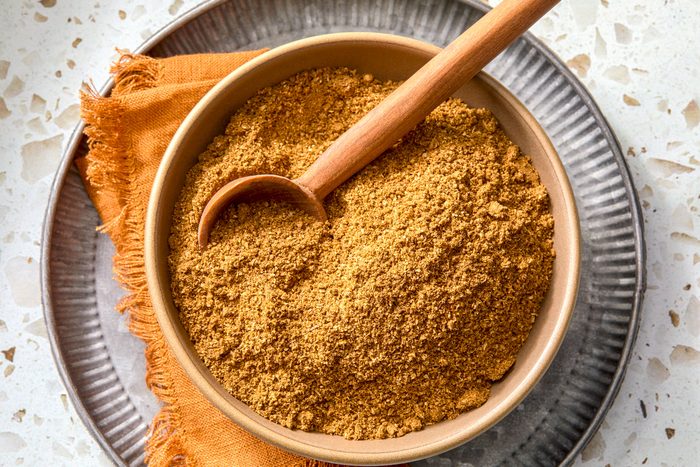 Garam Masala in a bowl on a plate with a wooden spoon