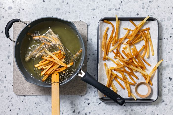 Frying potato strips in a oil in a large iron skillet until they are golden brown