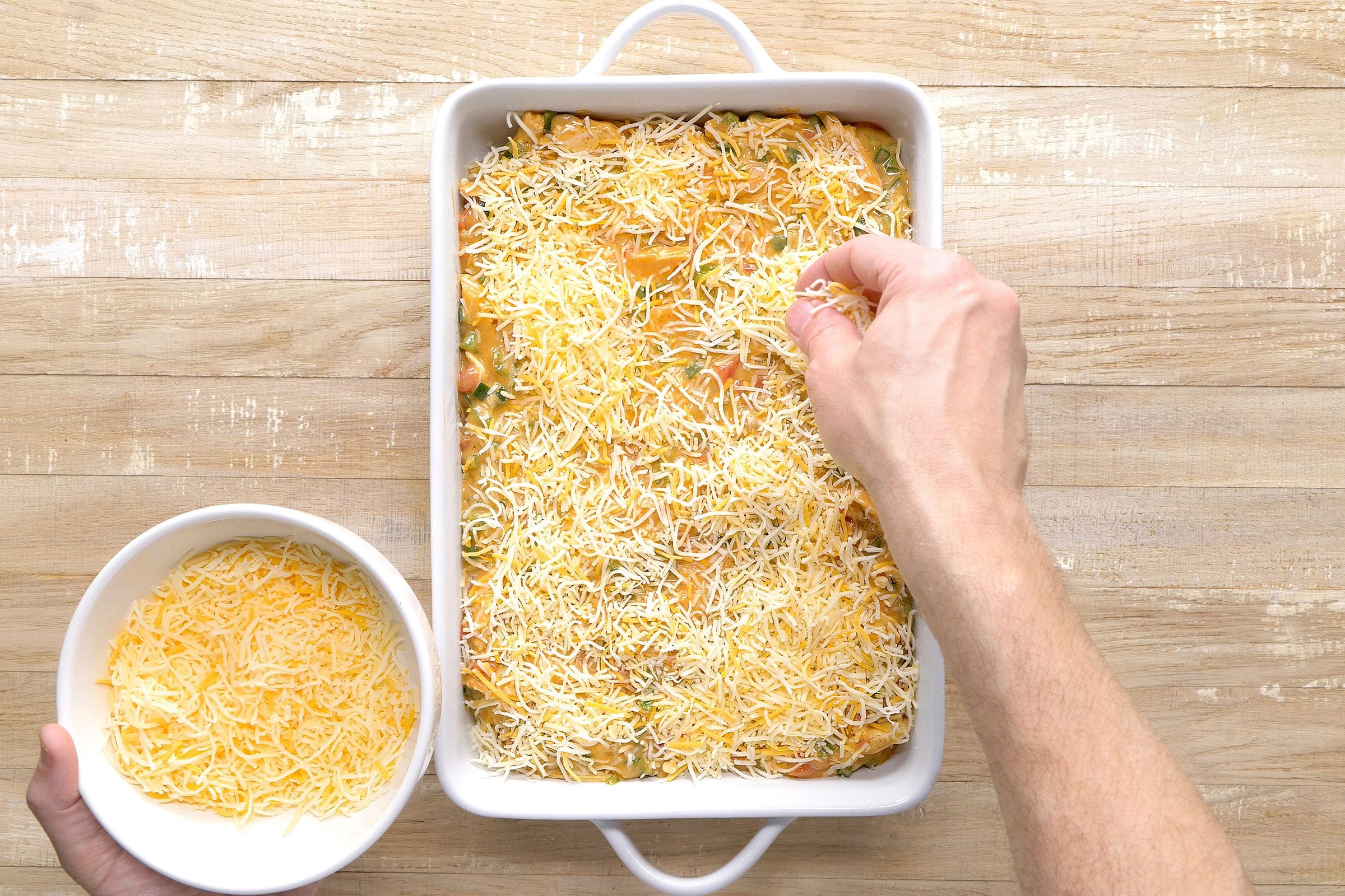 Cheese sprinkled on chicken mixture in a baking dish