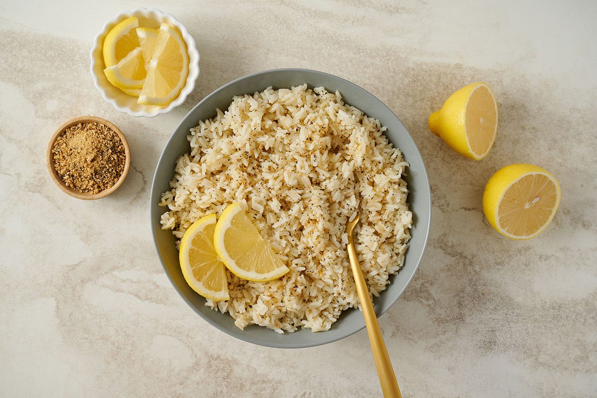Overhead view of the finished Taste of Home Lemon Rice, garnished with lemon wedeges and lemon-pepper seasoning in a serving bowl.