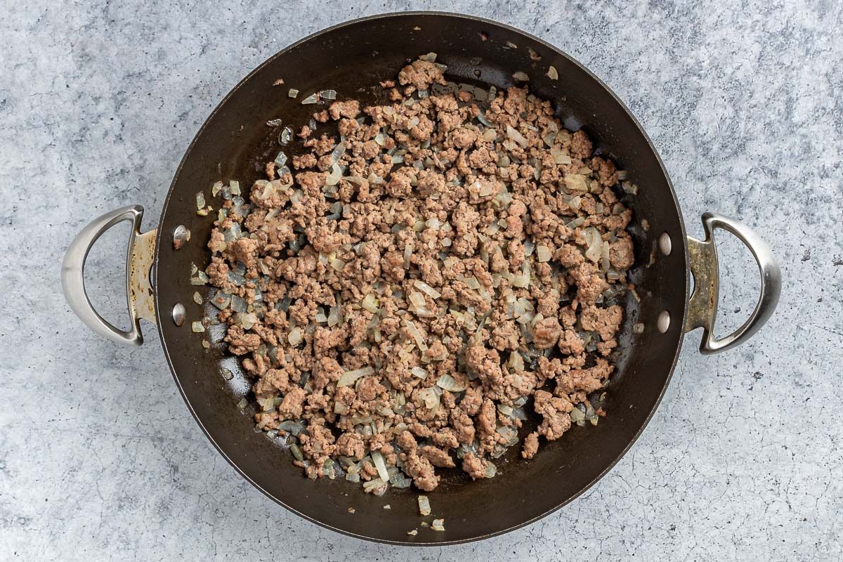 Taste of Home Nacho Casserole photo of the cooked beef and onion in a skillet.