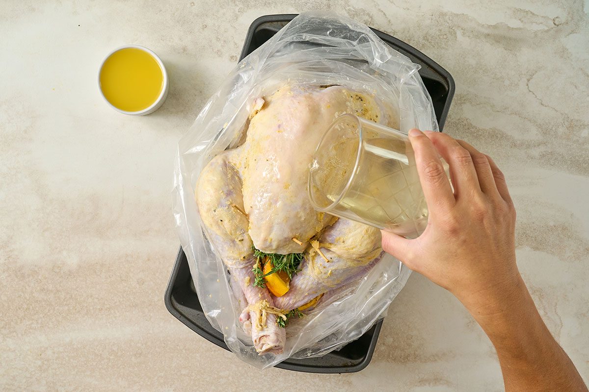 Overhead view of the seasoned turkey placed in the oven bag in the roasting pan, with champagne and orange juice poured over for the Taste of Home Orange Turkey recipe.