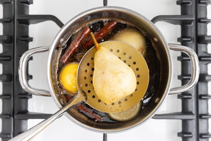 Pears being removed with slotted spoon.