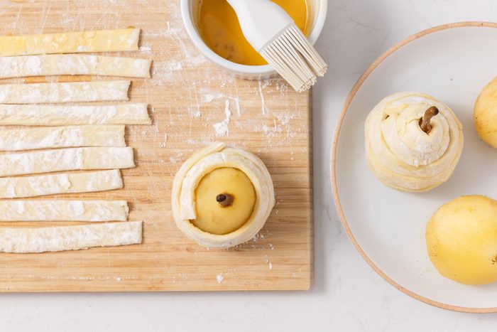 Pears being wrapped in puff pastry to be baked.