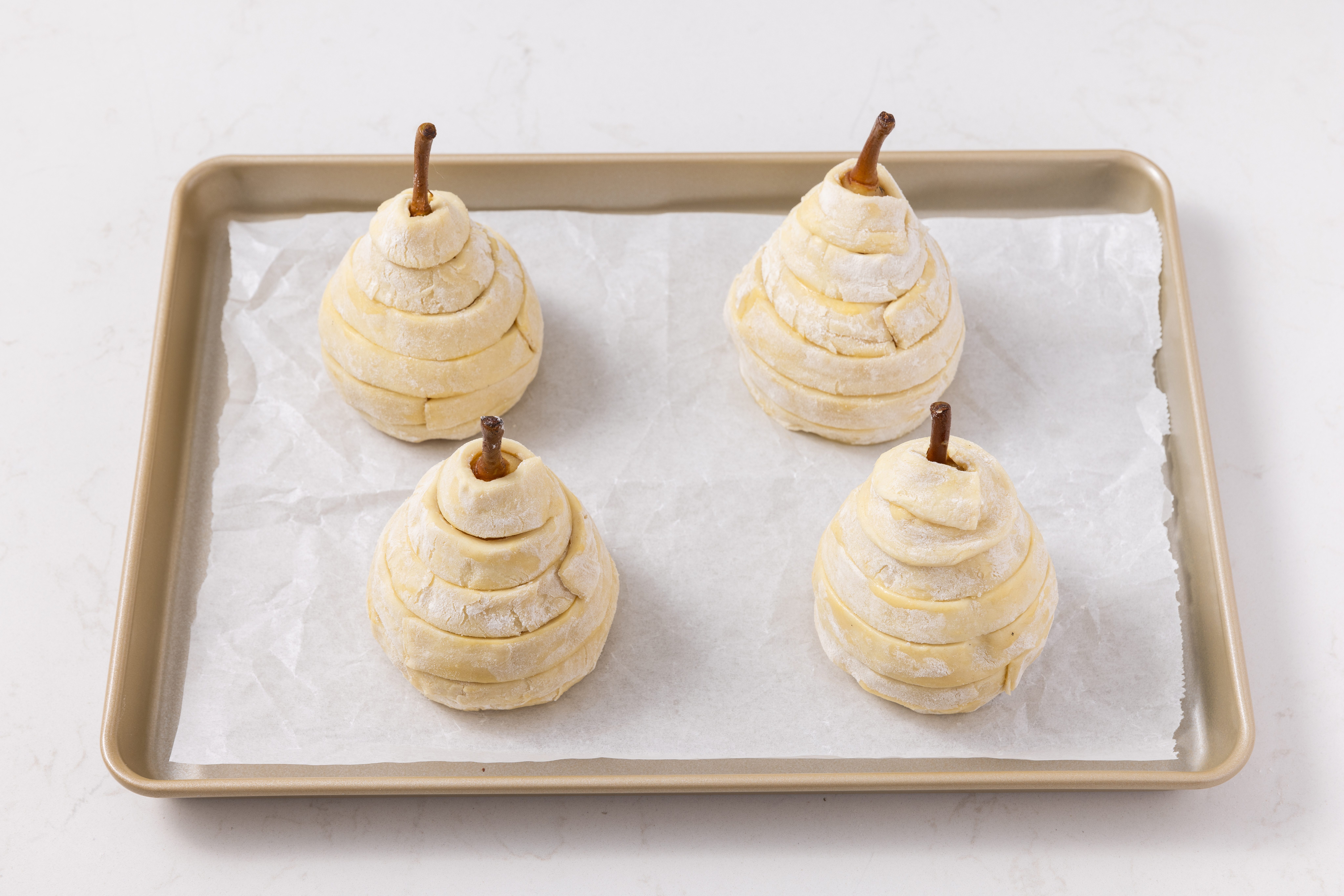 Pears wrapped in puff pastry and ready to go in the oven in baking sheet.