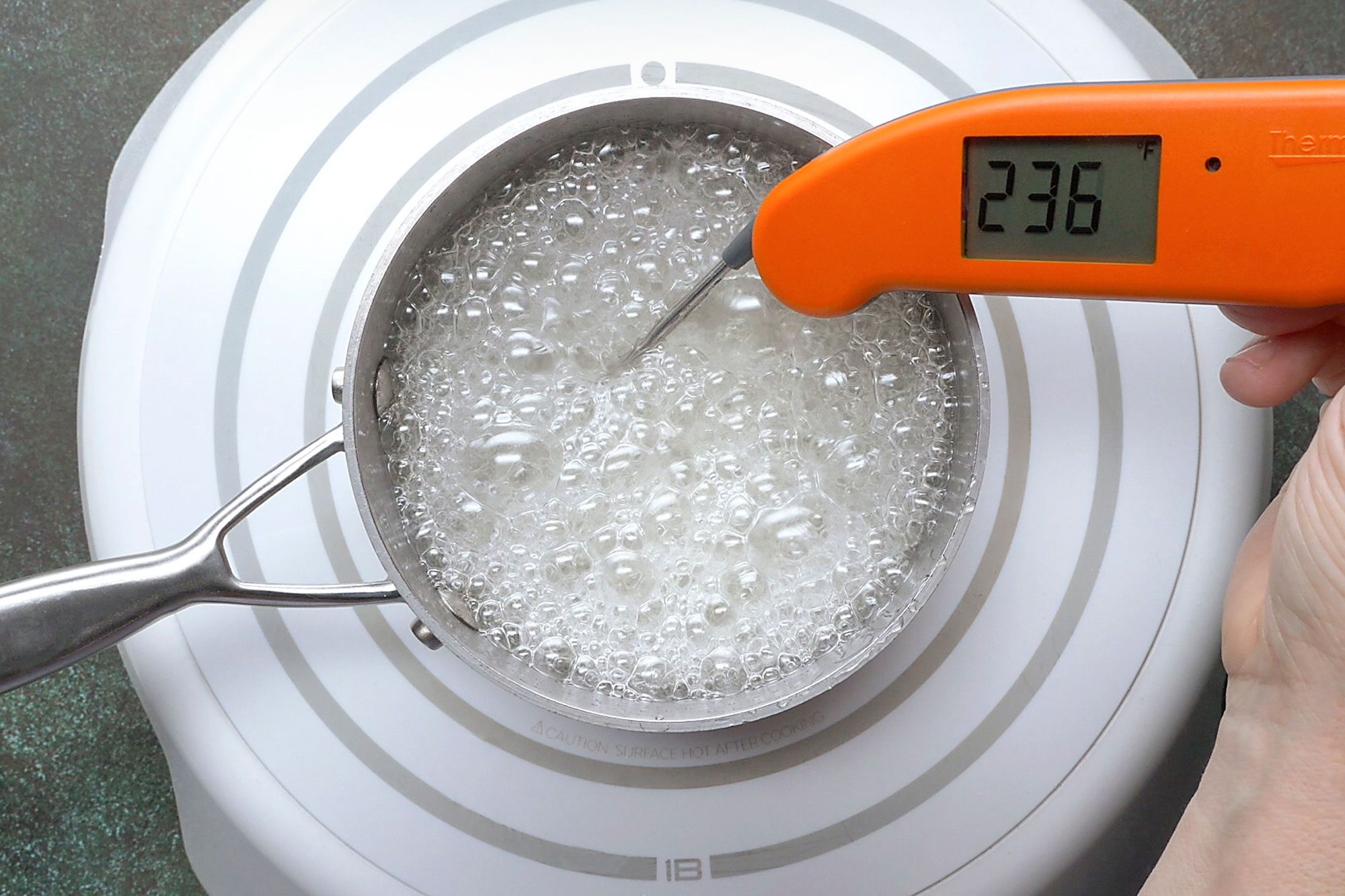 Overhead shot of a heavy saucepan combine the sugar; corn syrup; water and salt; cook over medium heat until a candy thermometer reads 235 degree; napkin; green marble surface;
