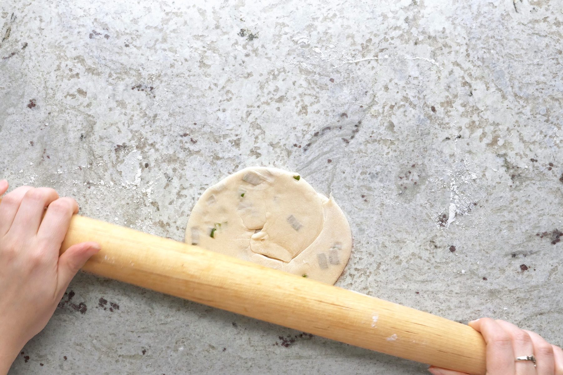 Using a rolling pin to roll the dough into a circular shape.