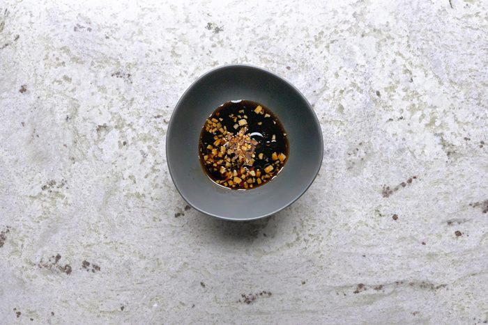 Mixing soy sauce, brown sugar, ginger, rice vinegar, sesame oil, and red pepper flakes in a small bowl to create a dipping sauce for the pancakes.