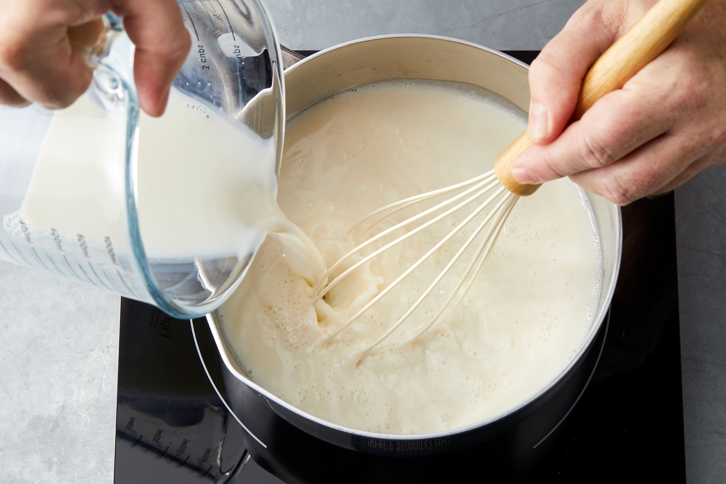 Adding milk to pasta sauce in a pan