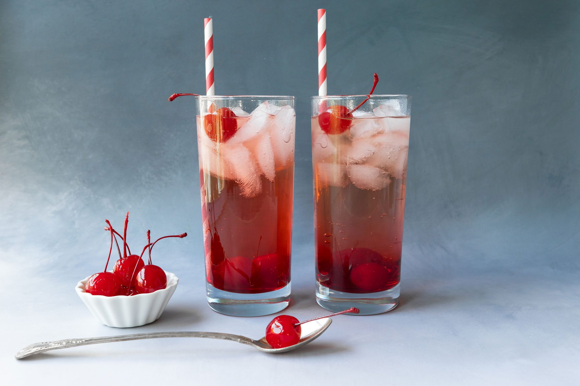 Garnish the drink with a stemmed maraschino cherry to serve and add a straw 