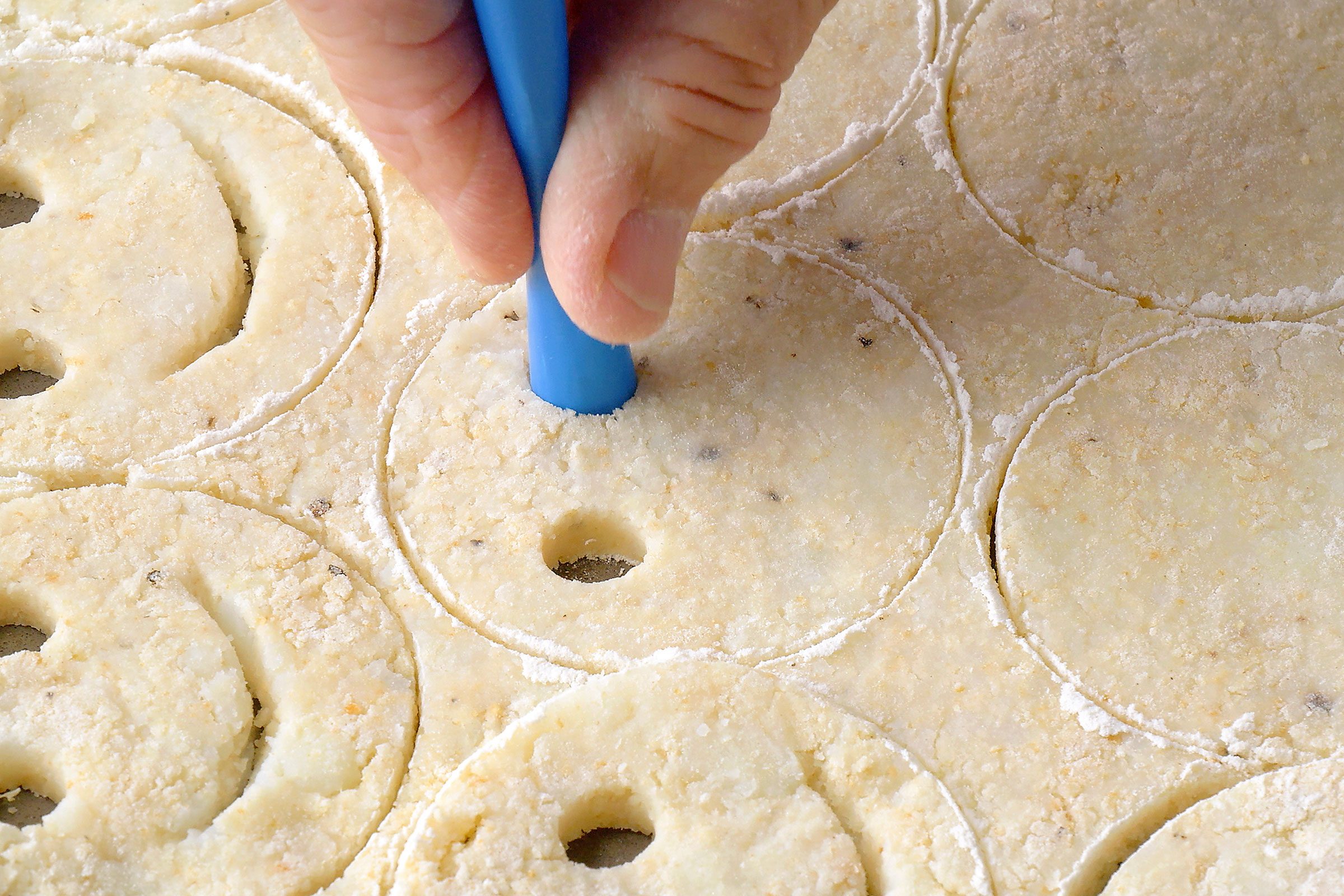 Using a blue straw to poke potato dough and make smiley eyes