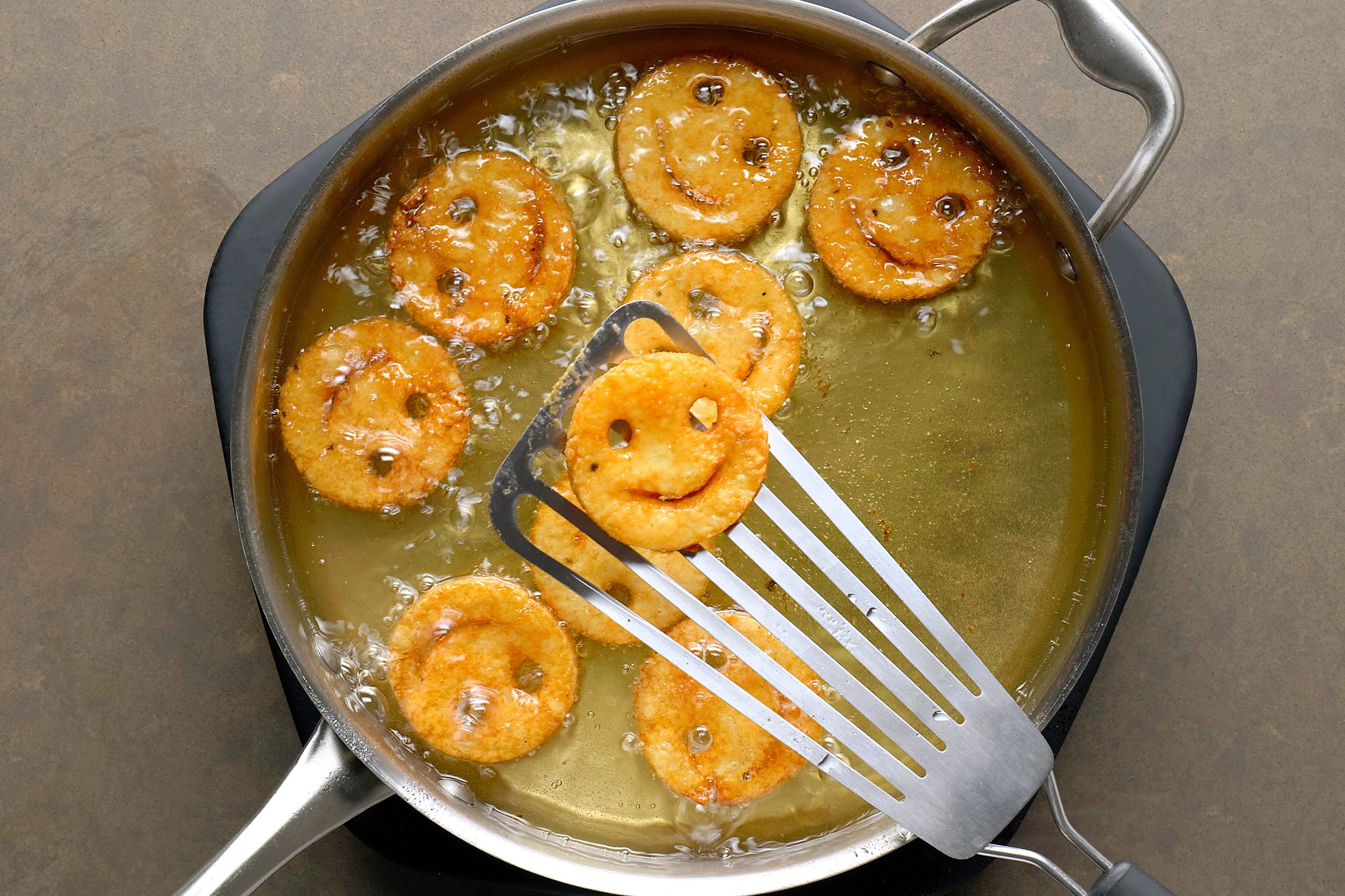 Frying potato smileys in oil in a pan