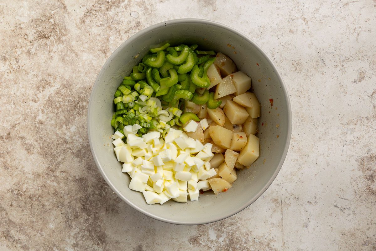 Taste of Home Sour Cream Potato Salad recipe photo of potatoes, egg whites, celery and onion in mixing bowl.