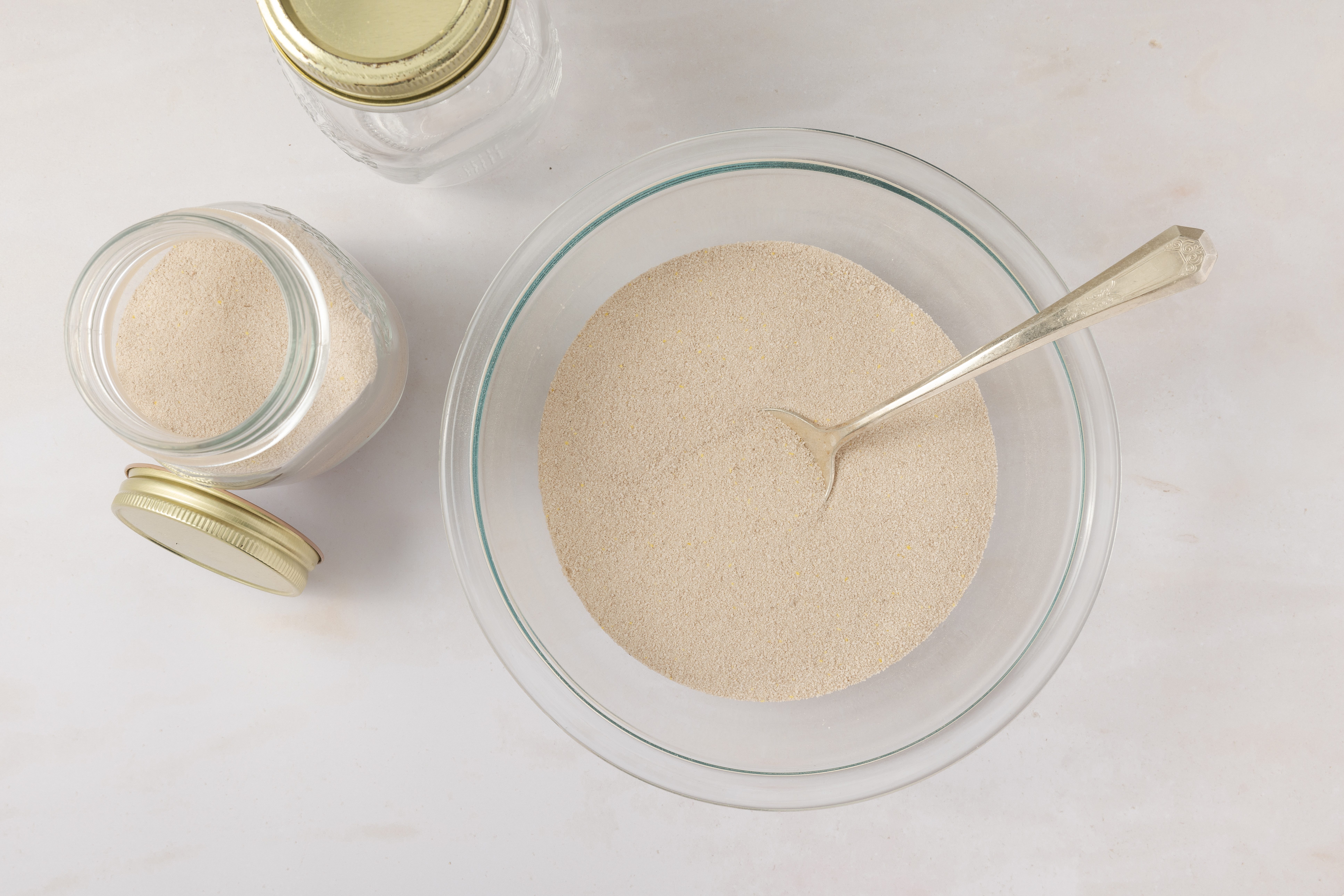 Spiced tea ingredients being combined in mixing bowl and stored in air tight containers.