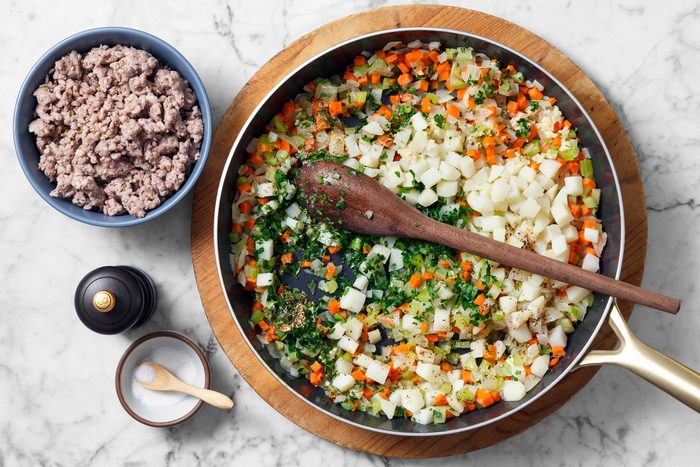 Overhead shot of stir in the potatoes; parsley; fennel; remaining 1 teaspoon salt; remaining 1/4 teaspoon pepper and reserved sausage; spoon; marble surface.